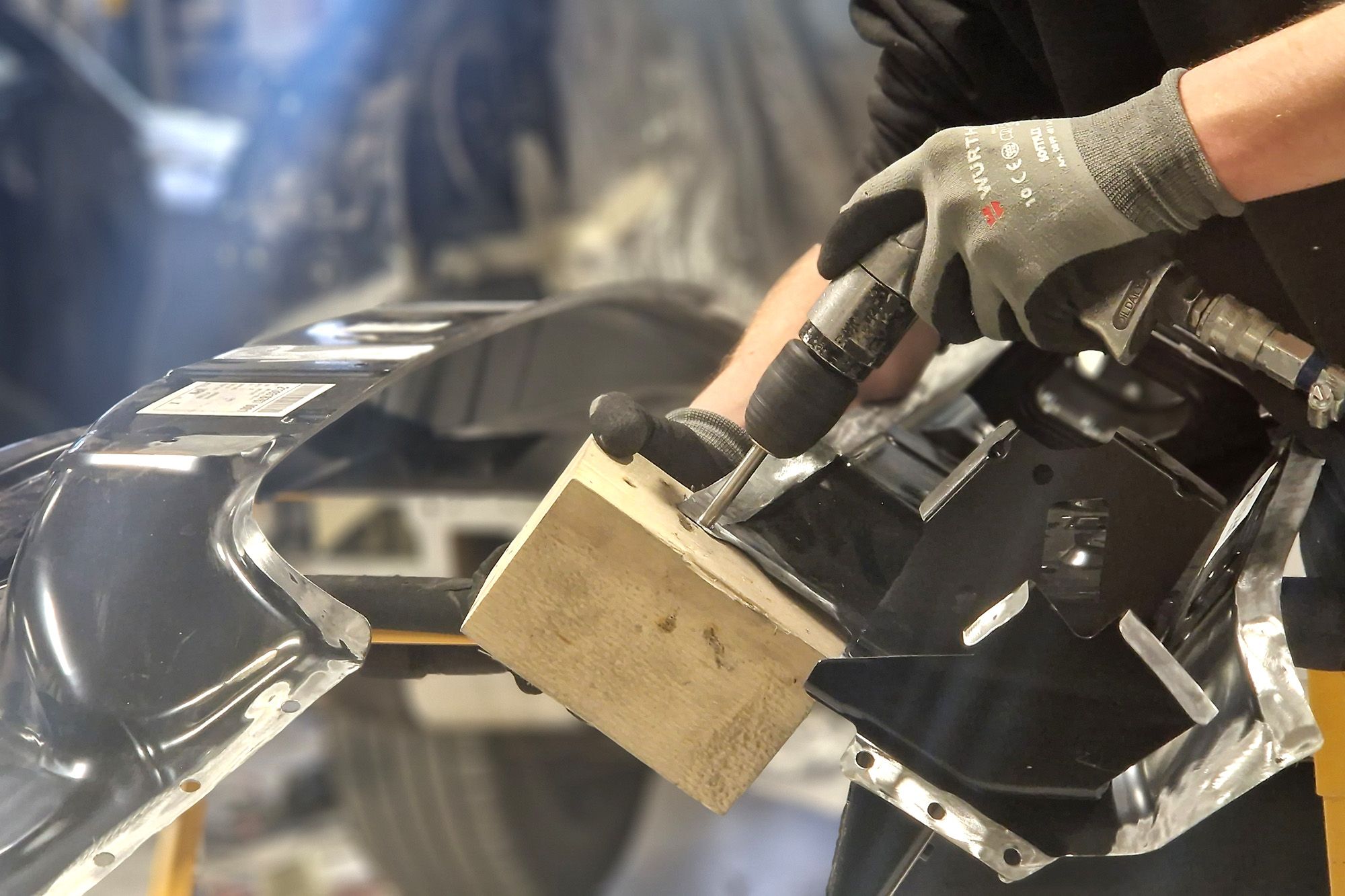 Panel worker drilling a rear bumper